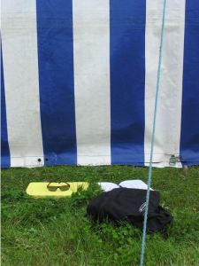 Rucksack, seat pad and sunglasses on the grass behind the marquee.