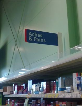 Sign over shelves in Tesco announcing 'Aches and Pains'
