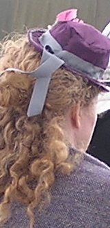 Lady wearing ribboned purple hat over long curly hair
